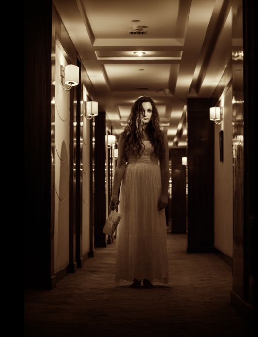 Ethereal woman in white standing in hotel lobby