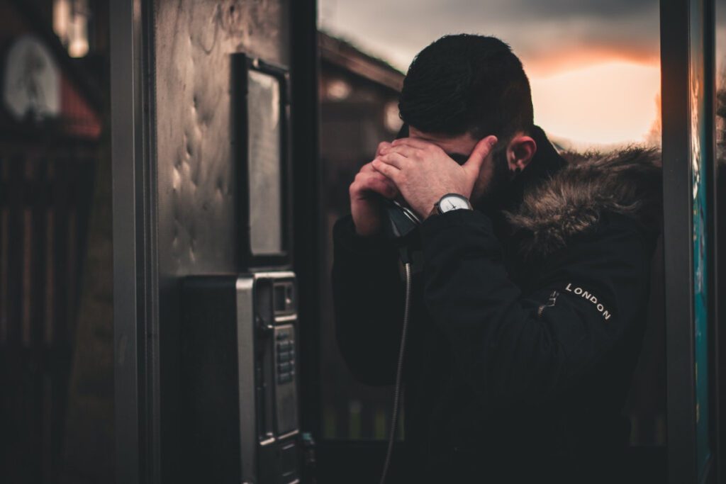 Distressed man making a phone call from a telephone booth